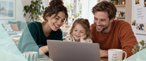 Family smiling while looking at a laptop together at home.