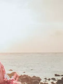 Woman with open Arms in front of the Ocean