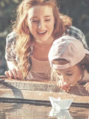 Au-pair with hostkids playing with paperboats