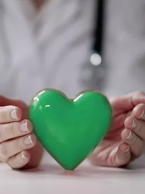 A doctor embraces a green heart with her hands