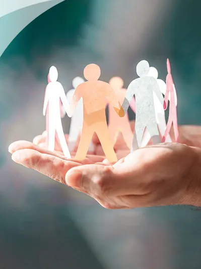 Hand holding diverse paper cut-out figures in a circle.